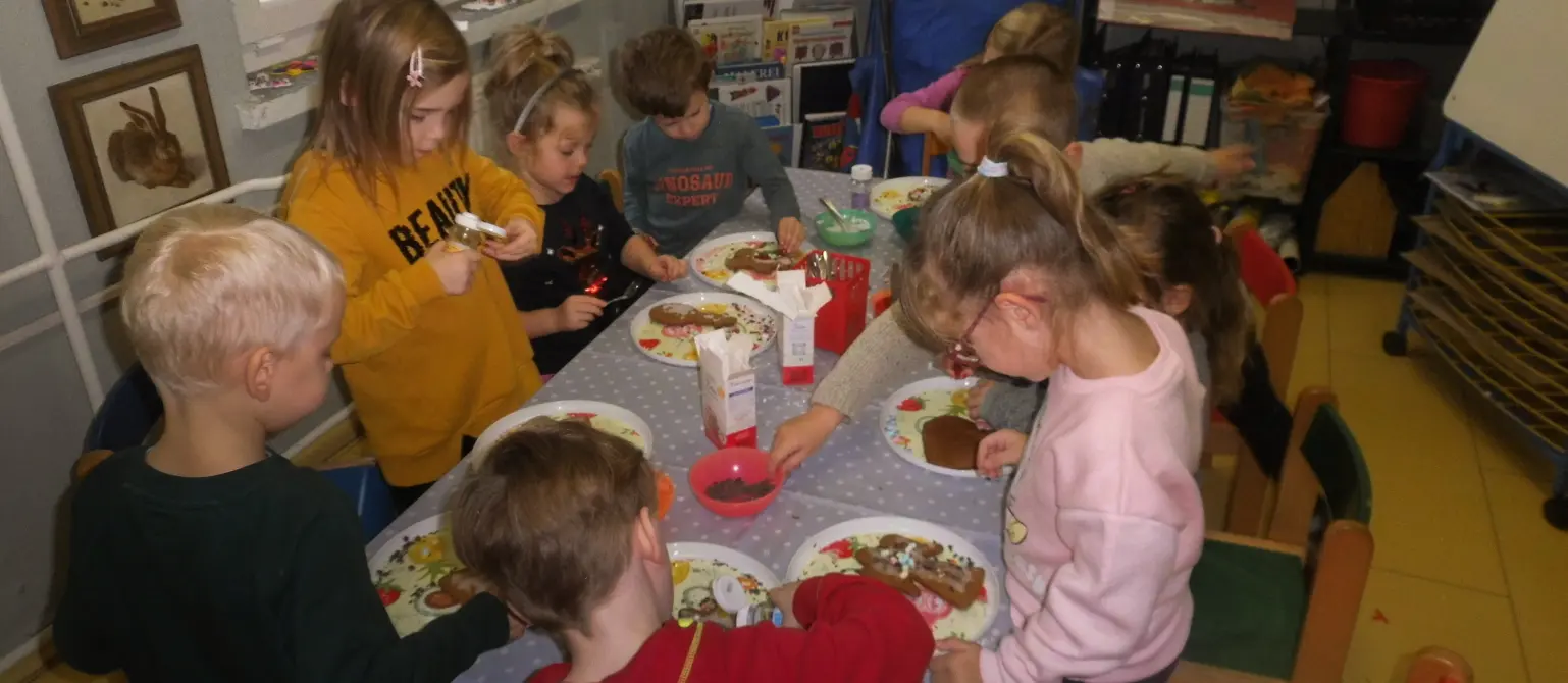 Eine Gruppe von Kindern dekoriert am Küchentisch frisch gebackene Lebkuchen.