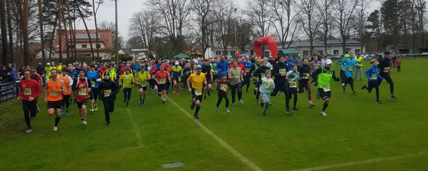 Mitglieder des Vereins Cottbuser Parkläufer laufen über einen Sportplatz.