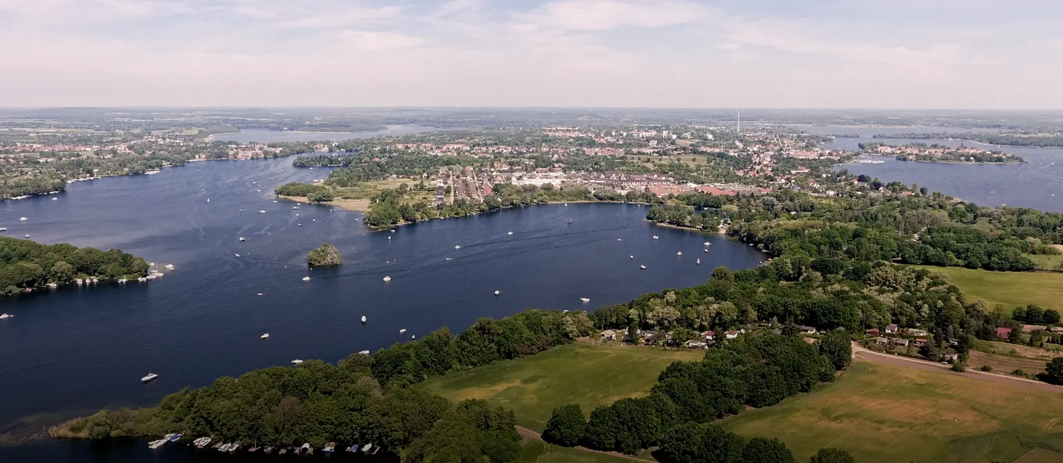 Ein Brandenburger See umgeben von Wald nahe einer Stadt
