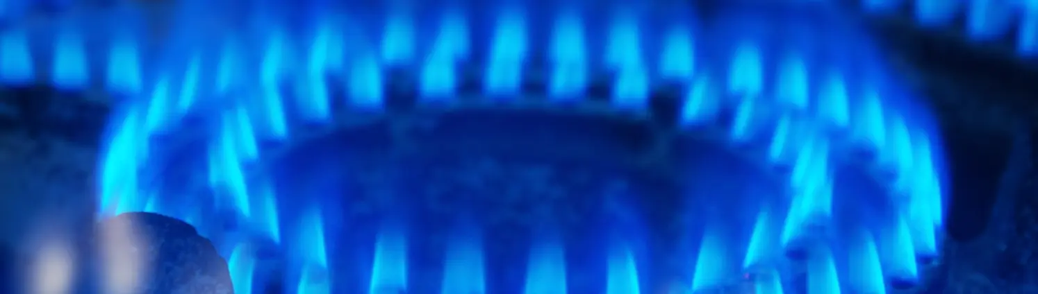 Nahaufnahme: Blau leuchtende Gasflamme an einem Gasherd.