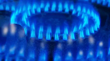 Nahaufnahme: Blau leuchtende Gasflamme an einem Gasherd.