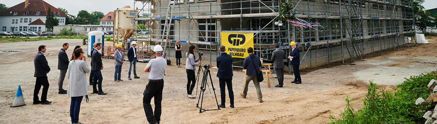 Richtfest für den Rohbau des Energiehauses der Energie Brandenburg in Michendorf. Menschen laufen über die Baustelle.