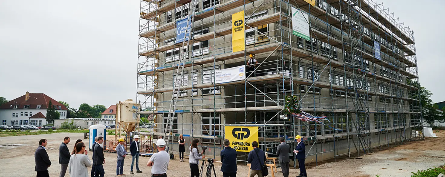 Richtfest für den Rohbau des Energiehauses der Energie Brandenburg in Michendorf. Menschen laufen über die Baustelle.