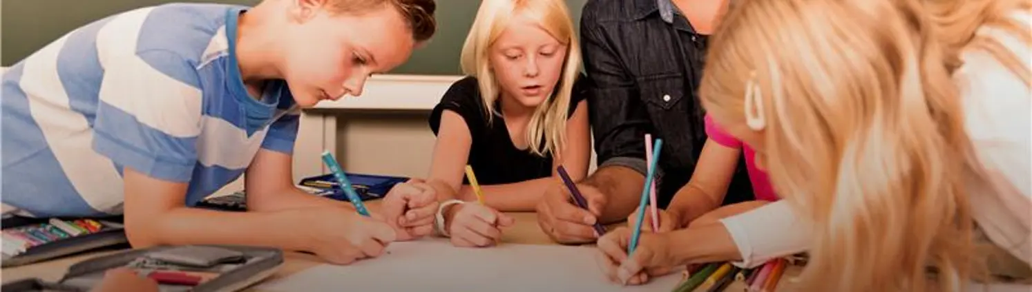 Kreative Ideen: Ein Lehrer skizziert mit einer Gruppe von Schülerinnen und Schülern Ideen für ein nachhaltiges Mehrgenerationenhaus.