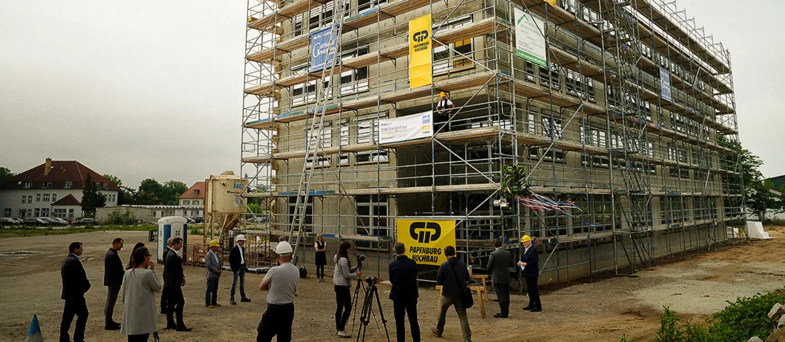 Richtfest für den Rohbau des Energiehauses der Energie Brandenburg in Michendorf. Menschen laufen über die Baustelle.