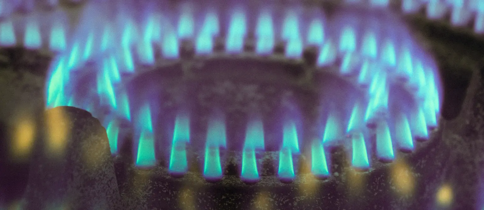 Nahaufnahme: Blau leuchtende Gasflamme an einem Gasherd.