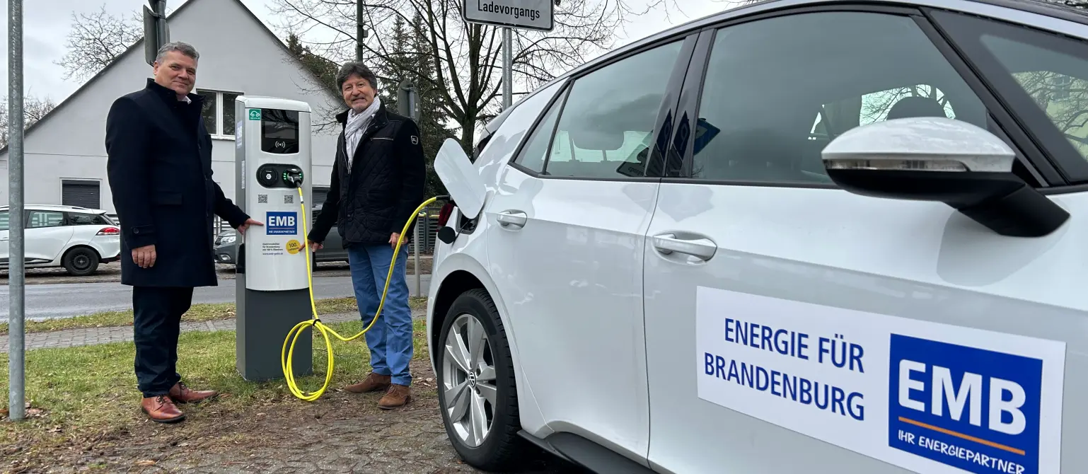 Geschäftsführer Dr. Jens Horn und Filippo Smaldino, Bürgermeister Mühlenbecker Land, laden ein weißes E-Auto an einer Ladesäule in Mühlenbeck.