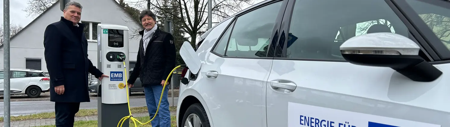 Geschäftsführer Dr. Jens Horn und Filippo Smaldino, Bürgermeister Mühlenbecker Land, laden ein weißes E-Auto an einer Ladesäule in Mühlenbeck.