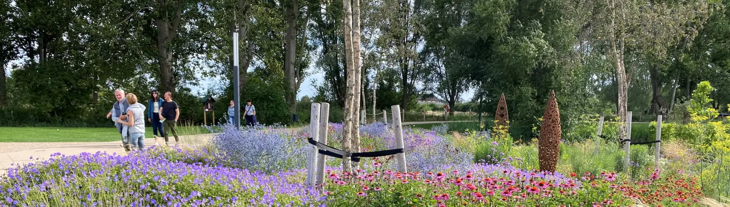 Ein prachtvoll blühendes Beet auf der Landesgartenschau Beelitz 2022. Im Hintergrund Menschen, die flanieren.